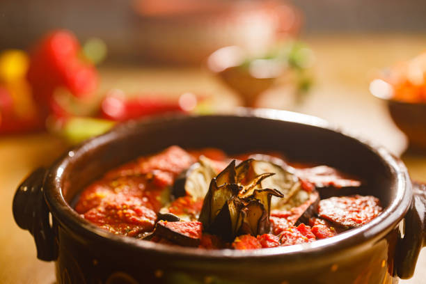 Close up of roasted eggplant with tomato sauce in crockery.