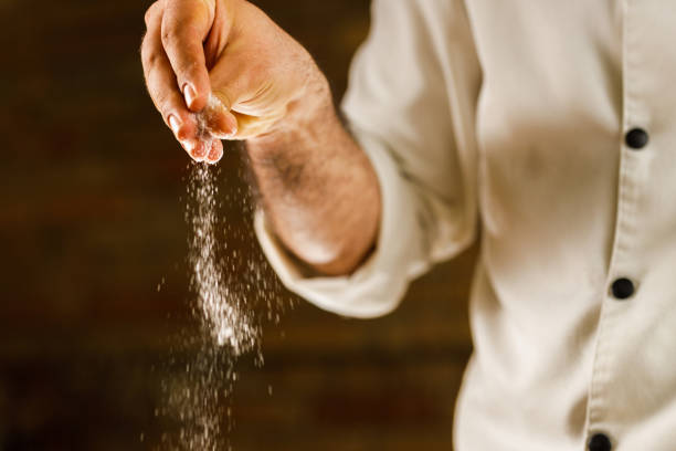 gros plan d’un chef ajoutant du sel à sa recette. - saupoudrer photos et images de collection