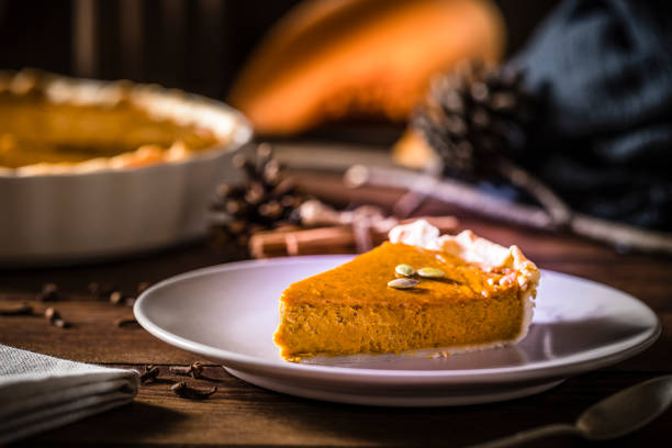 Front view of a slice of pumpkin pie on a rustic wooden table