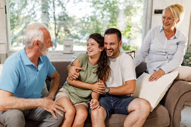 Happy couple talking to mature couple at home. Cheerful couple having fun while talking to senior couple at home. father in law stock pictures, royalty-free photos & images