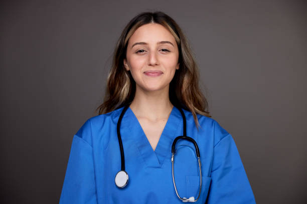 Headshot of a nurse looking at the camera with a stethoscope. Young woman studio portrait smirking stock pictures, royalty-free photos & images