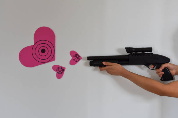Asian lady playing with a toy shotgun, shooting out pink heart-shaped targets.