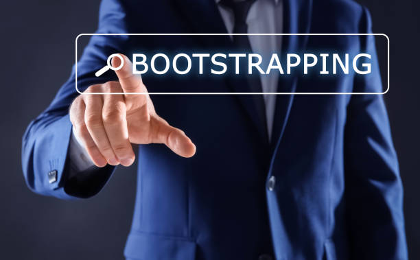 istock Businessman touching virtual screen with word BOOTSTRAPPING in search bar against dark background, focus on hand 1339991414