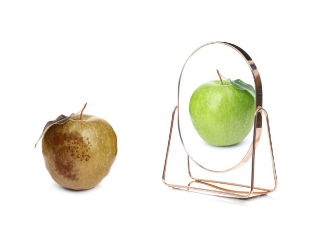 istock Spoiled apple and mirror with reflection on white background 1339991762