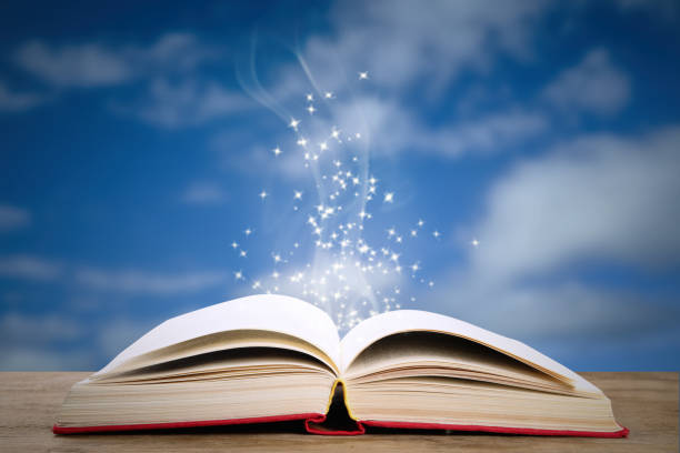 istock Open book with magic glowing on wooden table. Fairy tale 1339991991