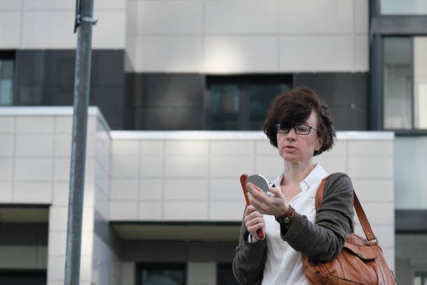 Woman is adjusting her make-up while waiting next to city building