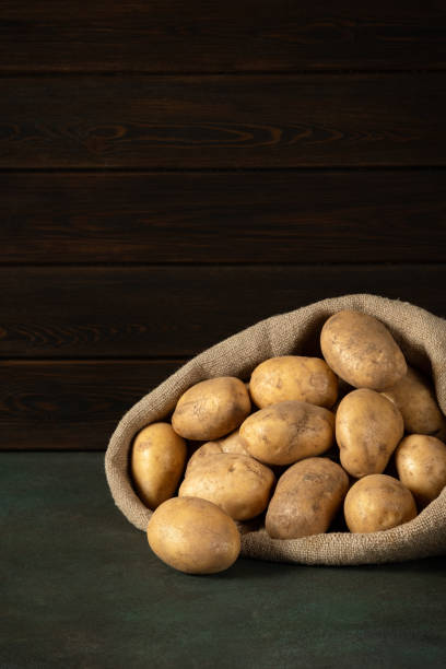 pommes de terre dans un sac couché sur la table. espace de copie, arrière-plan sombre. - raw potato organic rustic bag photos et images de collection