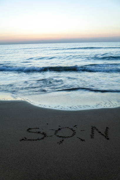 istock Sun drawing drawn on a beach at sunset 1339997968