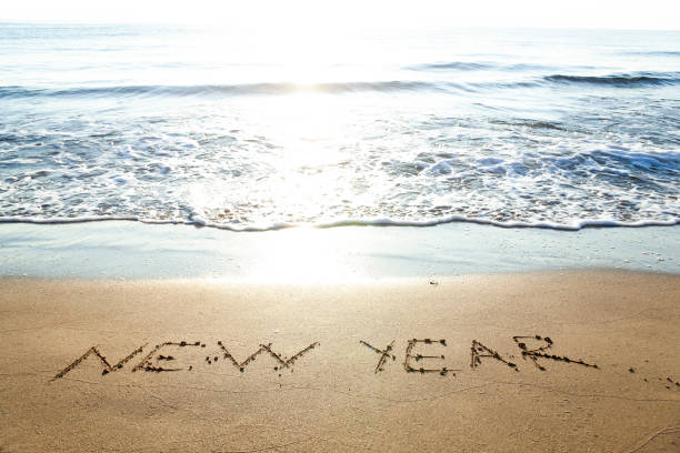 istock New Year hand drawn on sand summer beach background 1339997974