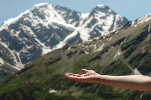 An empty open female palm against the background of beautiful mountains and blue sky. Closeup woman's hand showing something in empty copy space for advertisement.advertising text insertion.Layout for product. una palmera femenina abierta vacía sobre el fondo de hermosas montañas y cielo azul. primer plano de la mano de la mujer que muestra algo en el espacio de copia vacío para la inserción de texto publicitario.advertising. maquetación del producto.