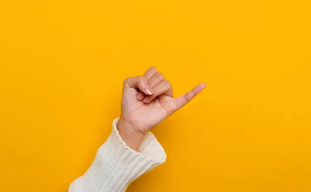 Photo of The promise of a white Asian woman's hand little finger split on yellow background gestures of commitment and reconciliationThe promise of a white Asian woman's hand little finger split on yellow background gestures of commitment and reconciliation