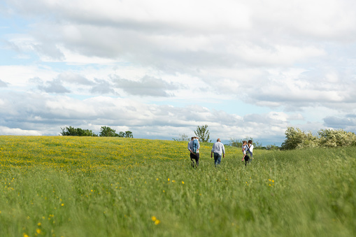 A wide-view shot of a mother, father, and grandfather walking with their two young daughters, they are at their farm in North East, England.