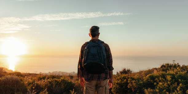 istock Rearview of a backpacker looking at the panoramic view on a hill 1340004432