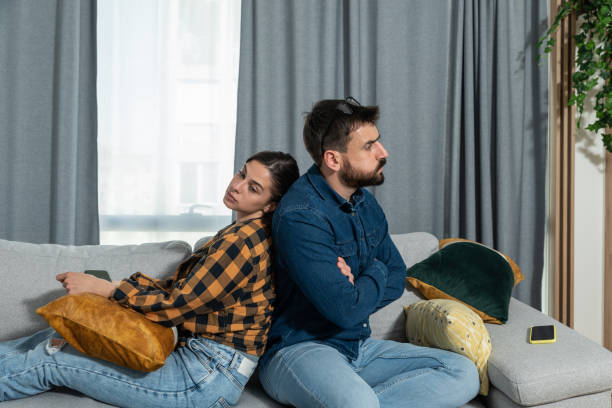 istock Young couple are arguing on the couch in their home and having difficulty and problems in a relationship and marriage sitting back to back and ignoring and not talking to each other 1340005794