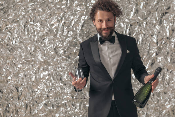 Mid Adult Man in Tuxedo Holding Champagne Man in formal attire holding champagne bottle and glasses. dinner jacket stock pictures, royalty-free photos & images