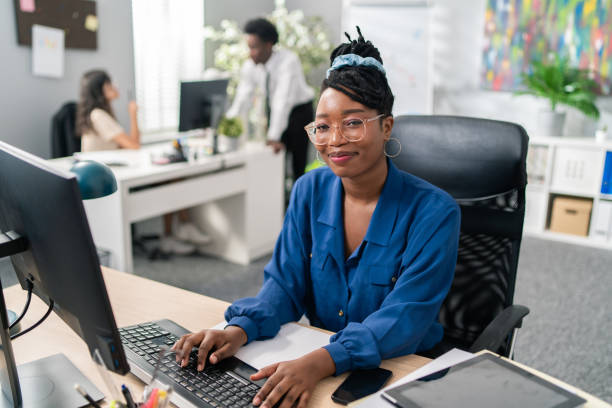 il rappresentante del servizio clienti educato ed elegante nelle grandi aziende si siede al computer, toccando le dita sulla tastiera, navigando in internet, preparando la documentazione, compilando rapporti, prendendo appuntamenti - segretaria foto e immagini stock