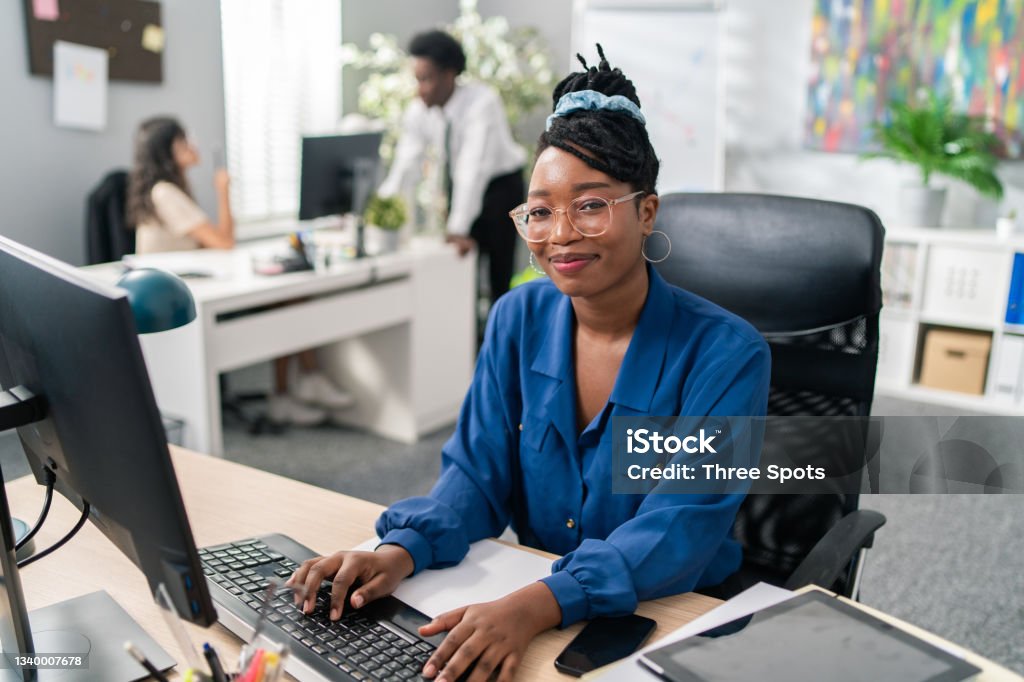 Polite, elegant customer service representative in large corporation sits at computer, tapping fingers on keyboard, surfing Internet, preparing documentation, filling out reports, making appointments Secretary Stock Photo