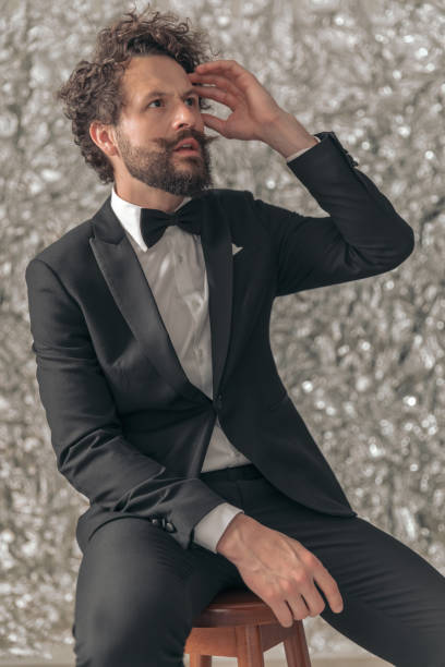 Portrait of Mid Adult Man in Tuxedo Bearded man in tuxedo standing against tin foil background. dinner jacket stock pictures, royalty-free photos & images