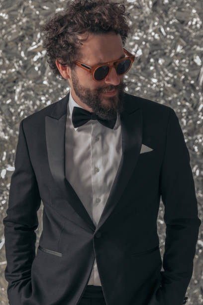 Portrait of Bearded Man in Tuxedo Man in formal attire wearing sunglasses and standing against tin foil background. dinner jacket stock pictures, royalty-free photos & images