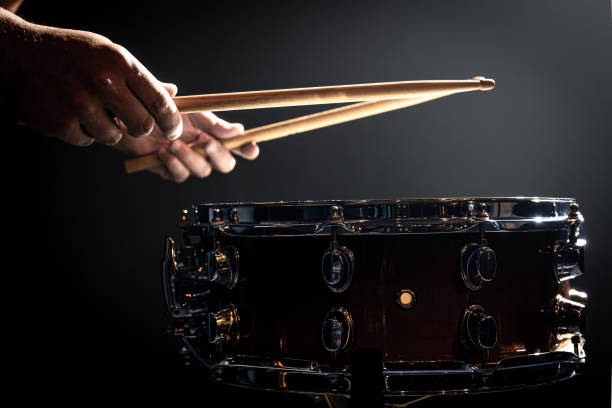 istock Snare drum and drummer's hands hitting drumsticks against a dark background. 1340008988