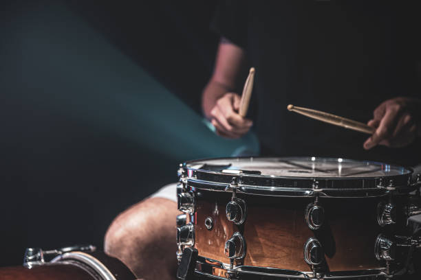 istock Drummer playing drum sticks on a snare drum on black background copy space. 1340014059