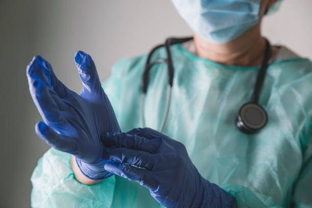 trabajador médico poniéndose guantes de látex - surgical glove fotografías e imágenes de stock