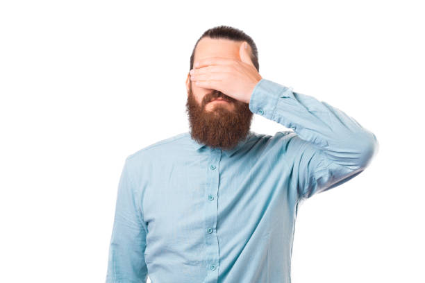istock Bearded man is covering his eyes over white background. 1340015203