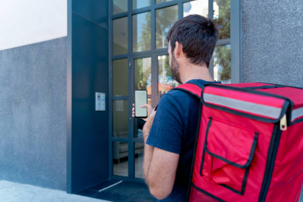 istock Delivery man with smartphone delivering parcel box . 1340015863