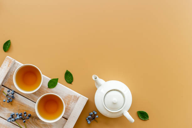 istock Black tea in cups with white teapot and green leaves 1340016671