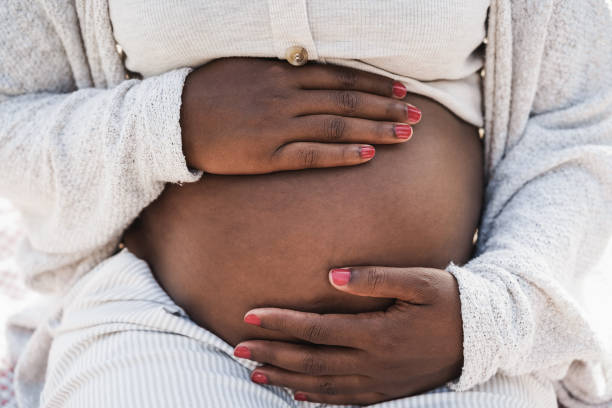 Close up of african pregnant woman holding her belly - Focus on hands stock photo