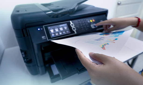 istock Office worker prints paper on multifunction laser printer. Copy, print, scan, and fax machine in office. Document and paper work. Print technology. Hand press on photocopy machine and holding paper. 1340021984