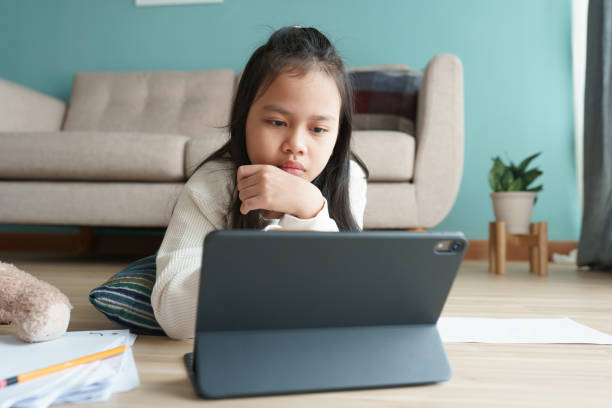 istock Asian little girl using tablet while lying at home 1340022437