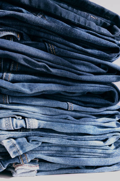 istock a pile of blue jeans on a grey background. Vertical. Close up 1340022987