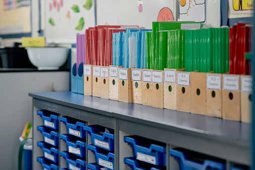 A close-up view of an organized classroom with color-organized wooden desk tidys lined up on the top of a set of classroom drawers. The school is based in Hexham in the North East of England.