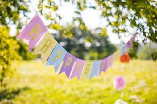 Text happy birthday on colorful paper flags in the park. High quality photo