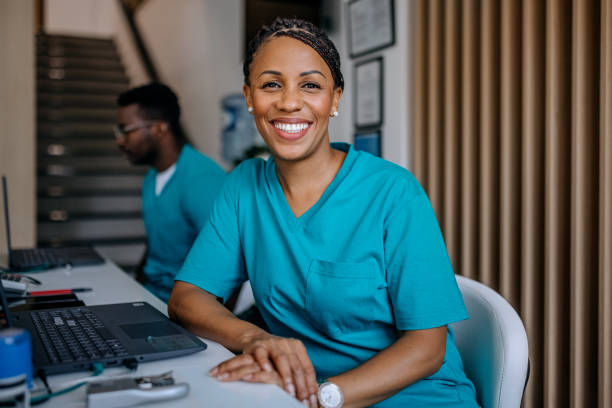 Happy nurse working at the hospital Photo of nurse working at the nurse station at the hospital and looking at the camera smiling assistant stock pictures, royalty-free photos & images