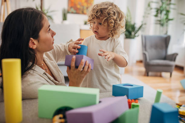 istock Cute curly boy and mom playing on the sofa 1340030755