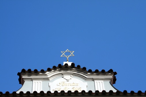 Golden star of David against a blu sky. The latin words \