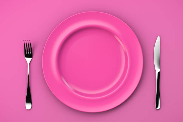 istock An empty pink plate on a pink table and a fork with a knife. Top view 1340037346