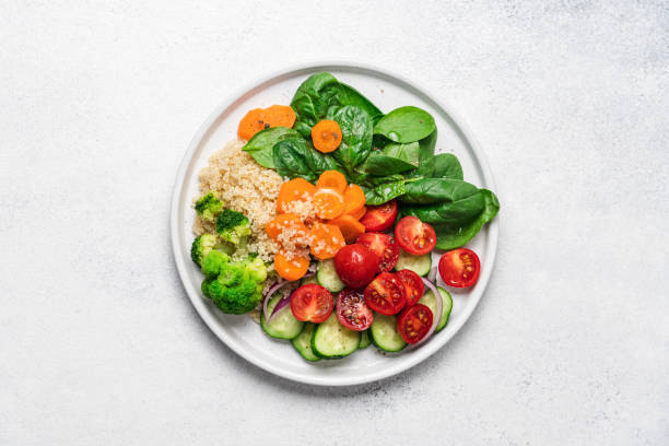 Salad with quinoa, spinach, broccoli, tomatoes, cucumbers and carrots stock photo