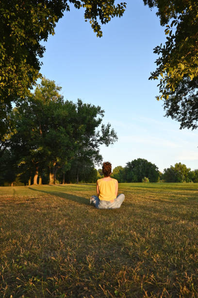 istock Woman sitting in a field at sunset 1340044960