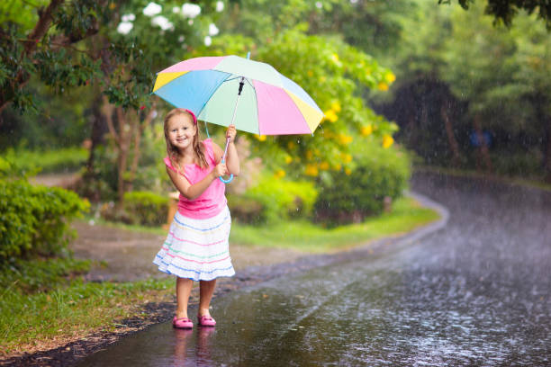 istock Kid with umbrella playing in summer rain. 1340045644