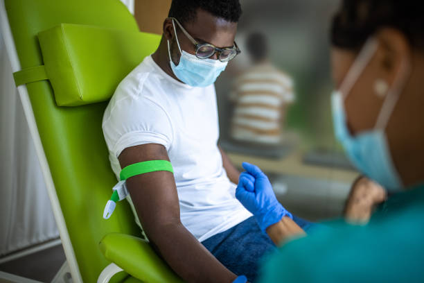 Young man on blood donation at medical clinic Young man on blood donation at medical clinic, nurse and him are wearing protective face masks for protection against coronavirus blood bank stock pictures, royalty-free photos & images