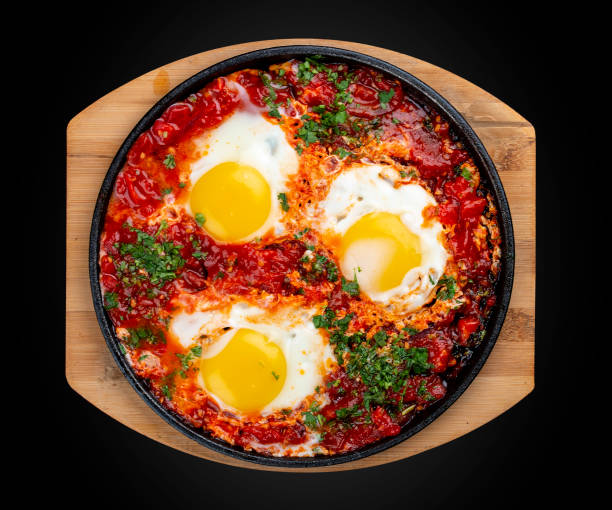 istock Scrambled eggs at home with tomatoes in a frying pan.  On a black background. Breakfast 1340049573