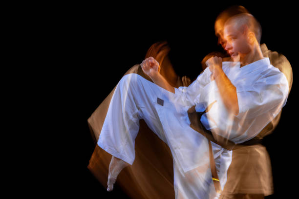 istock Man in white kimono training karate over black background. Mixed light effect 1340049645