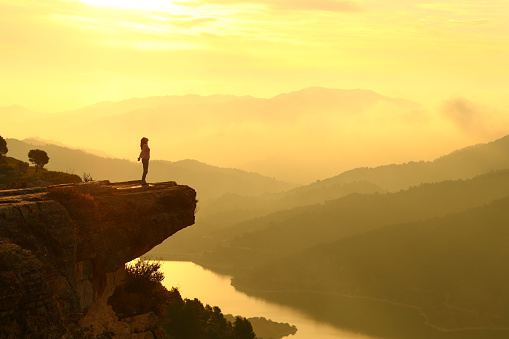 Mujer respirando en la cima de un acantilado al amanecer en la montaña photo