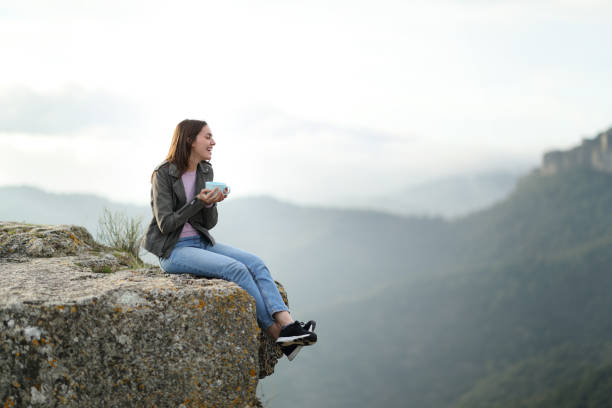 istock Happy woman contemplating views drinking coffee in a cliff 1340052613