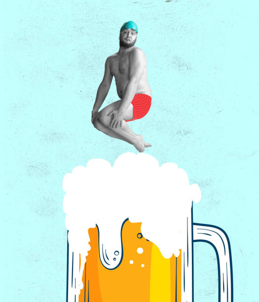 面白い陽気な水泳選手。赤い水泳のショートパンツと帽子をかぶったかわいい赤毛の男がビールの巨大なグラスに飛び込む。パーティー、フェスティバル、オクトーバーフェスト、ユーモア� - beer glass mustache beer color image ストックフォトと画像