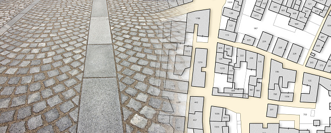 New paving made with grey stone slabs and small stone cube blocks interlocked with sand in curved shape in a pedestrian zone - concept with an imaginary city map