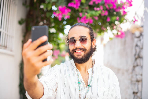 istock Young Man Taking Selfie in Flowery Street 1340057314